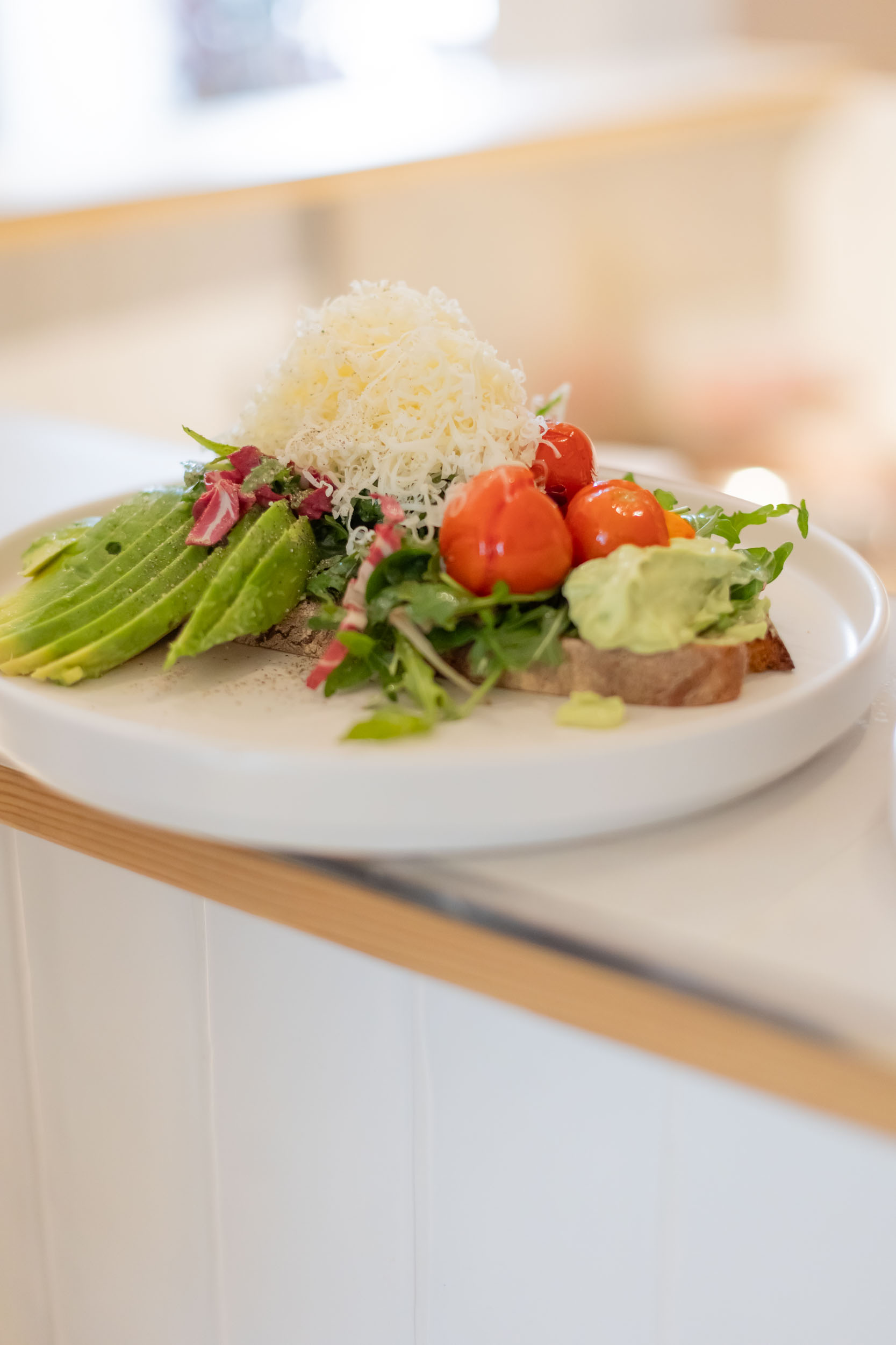 Krustenbrot Avocado mit frischer Avocado, gegrillten Tomaten, Avocado-Creme, Pflücksalat & gehobeltem Parmesan